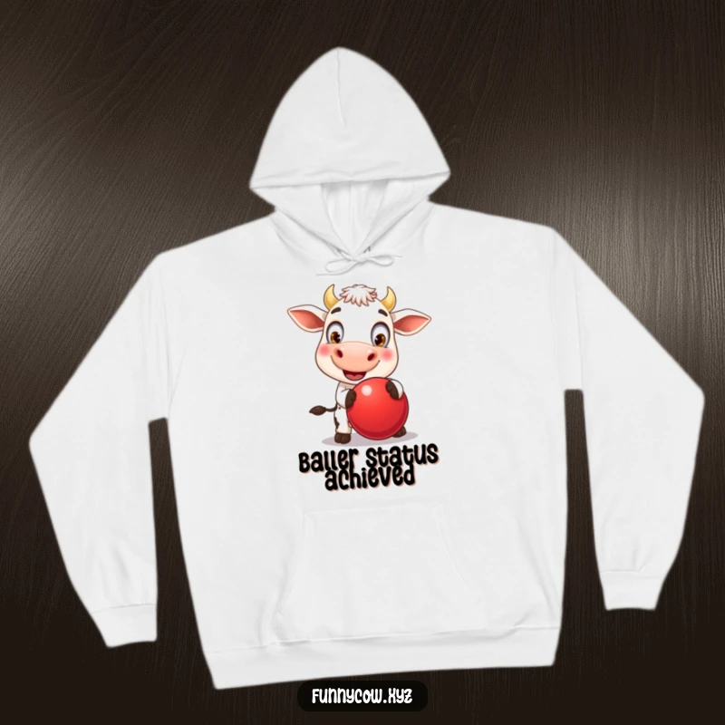 Funny hoodie depicting a joyful cow with massive, round eyes, energetically bouncing a large red ball, a symbol of boundless, happy play.