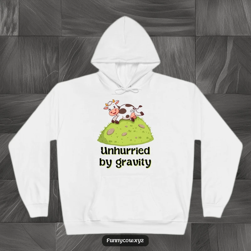 Funny hoodie depicting a cow gleefully sliding down a grassy hill on its behind, perfect for cozying up.