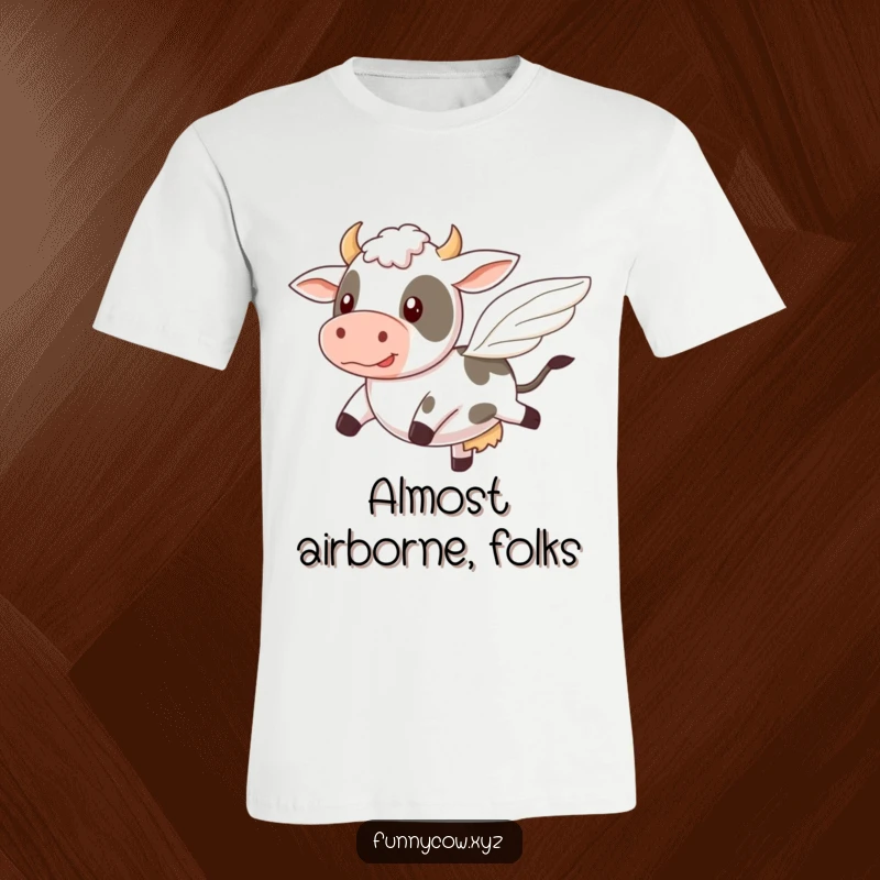 Funny T-shirt featuring a cow comically attempting to fly with tiny, wobbly wings, a whimsical depiction of trying.
