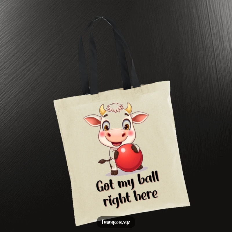 Funny tote bag illustrated with a beaming cow with oversized eyes, delightedly bouncing a huge red ball during a moment of pure, silly joy.